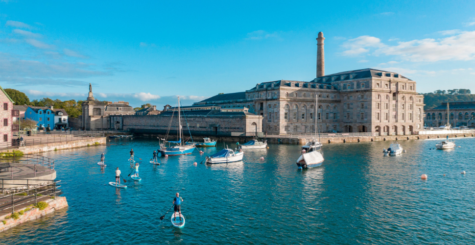 Stand up paddleboarders in front of the Royal William Yard